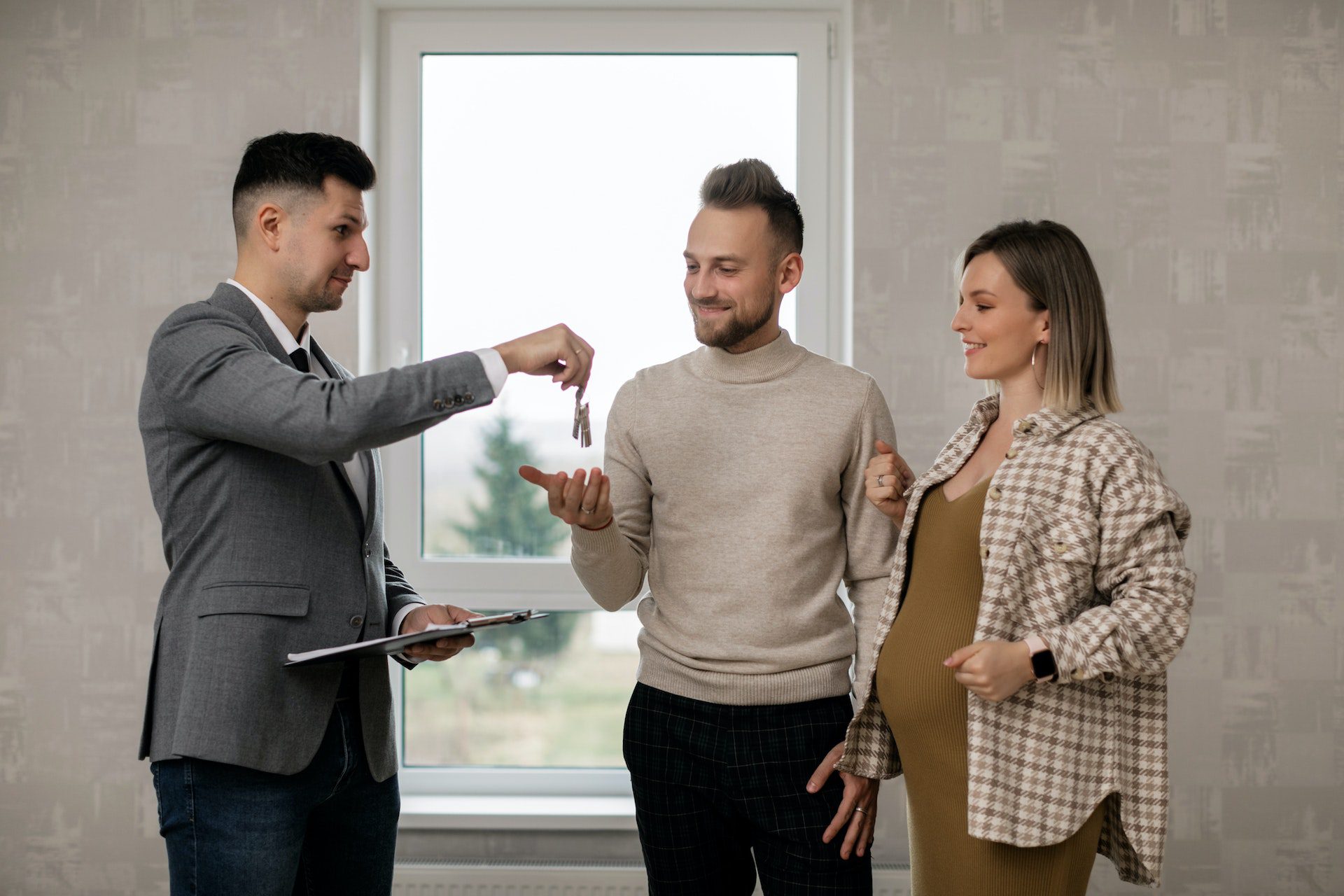 A Real Estate Agent Handing the Key to the New Homeowners A Real Estate Agent Handing the Key to the New Homeowners<br />
